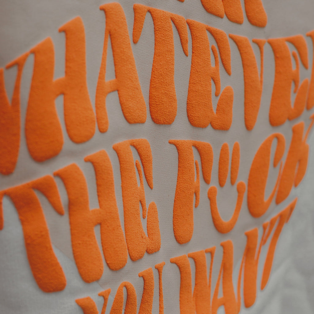 Beige sweater met beige hartje op de voorkant en oranje tekst in puff inkt op achterkant