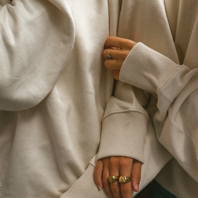 Beige sweater met beige hartje op de voorkant en oranje tekst in puff inkt op achterkant