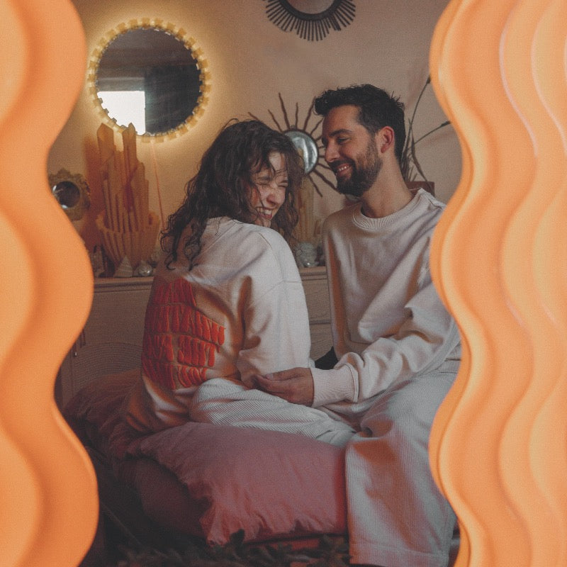 Beige sweater met beige hartje op de voorkant en oranje tekst in puff inkt op achterkant